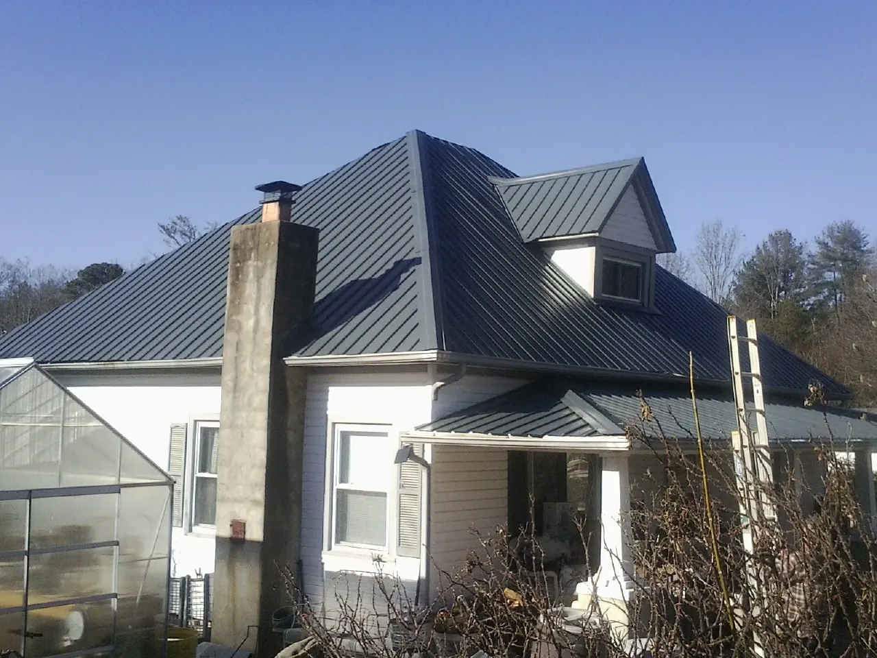 Dark blue standing seam metal roof on a white farmhouse with dormer — Slate & Tile Roof Repair by Roofing Brothers in Point Roberts