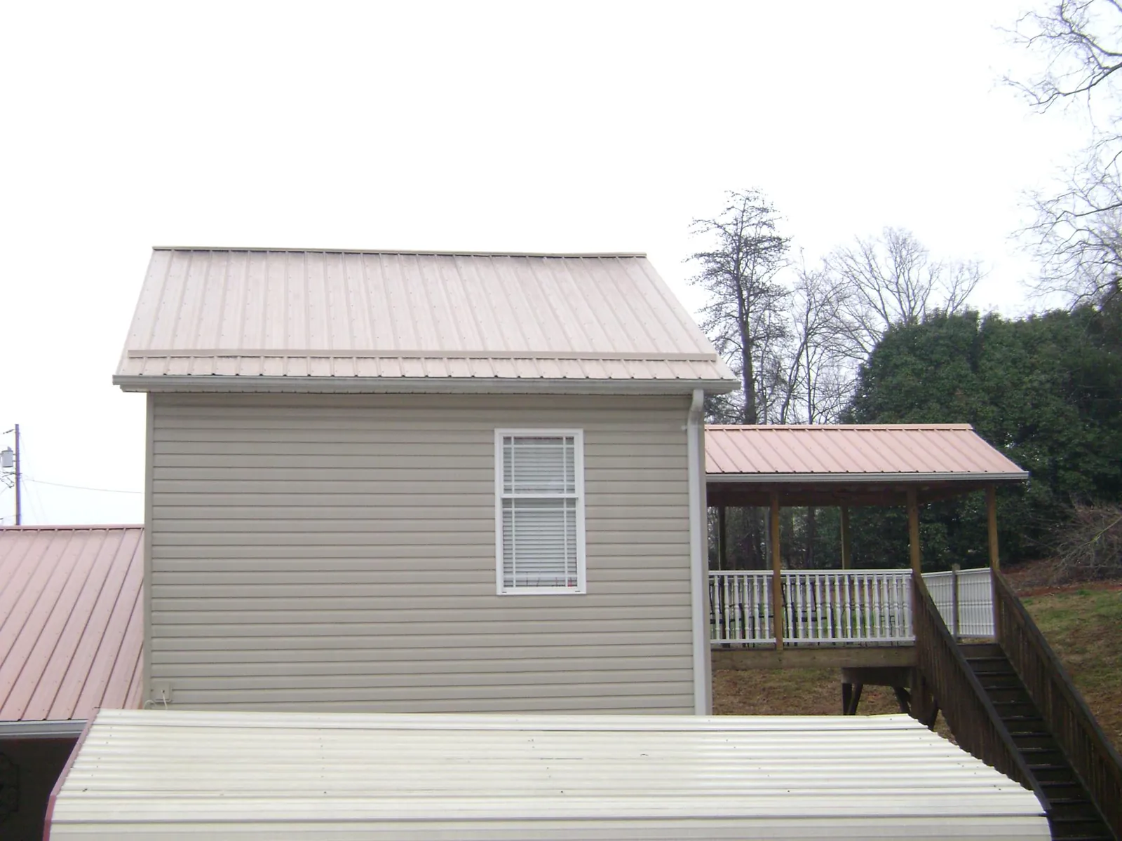 Tan metal roofs on a two story addition and attached porch, from a Roof Replacement job in Point Roberts