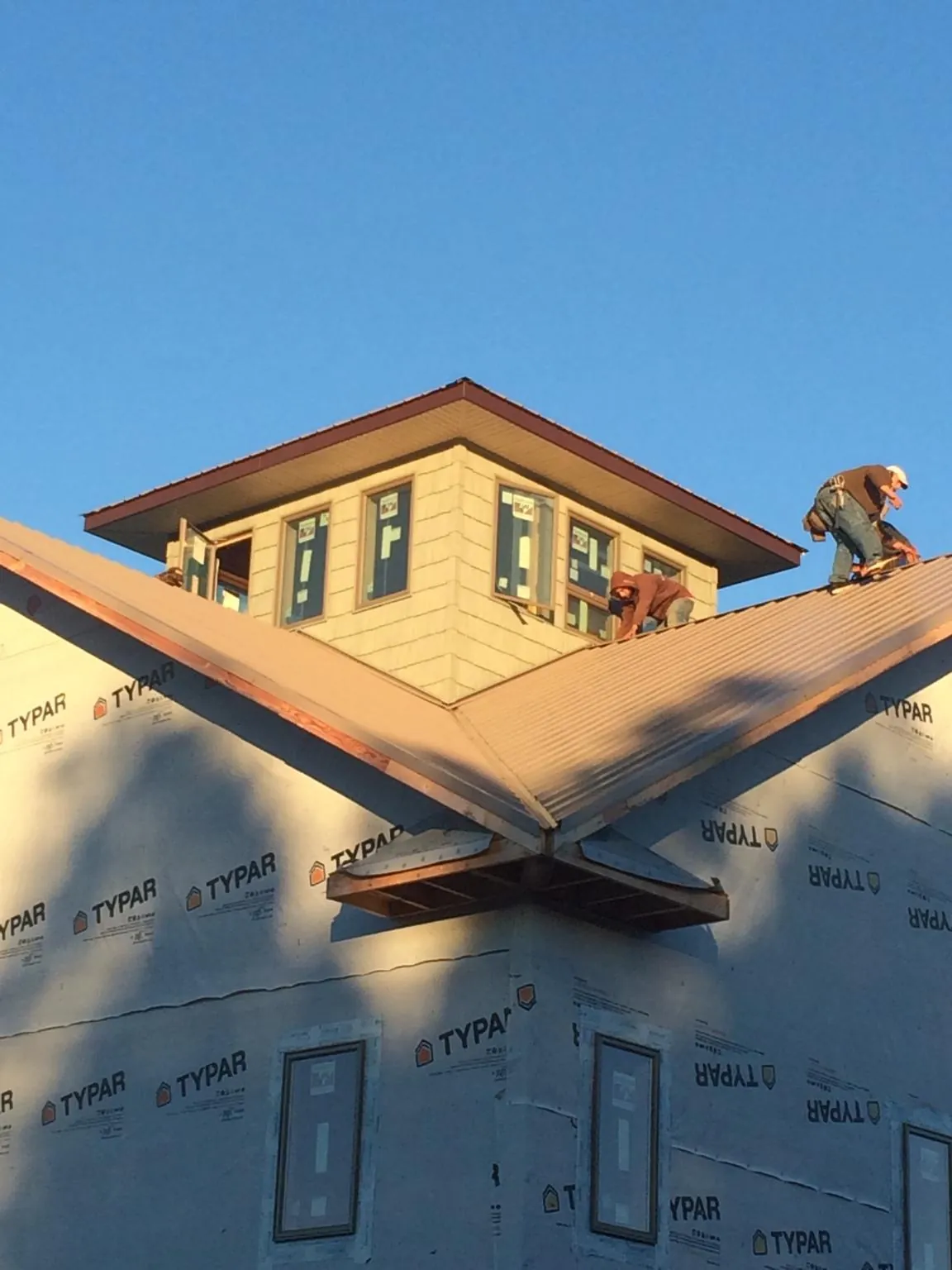 Roofers working around a rooftop cupola on a new metal roof at sunset — Roof Waterproofing in Point Roberts by Roofing Brothers